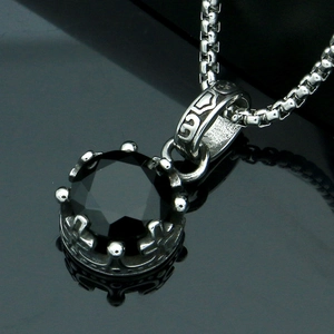 Macro detail of crown-shaped pendant with faceted black gemstone and box chain necklace