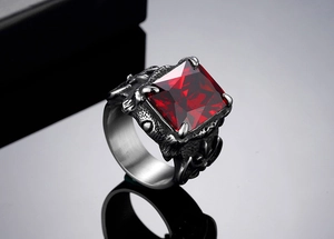 Detail of vintage gothic steel ring featuring a square red gemstone held by dragon claws