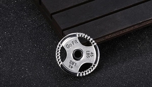 Macro shot of silver dumbbell pendant engraved with Go Fit 45 LBS on black background