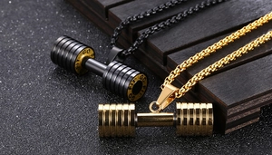 Gros plan de pendentifs haltères or et noir avec gravure GO FIT GO sur chaînes en acier