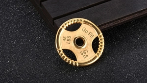 Detailed close-up of a gold dumbbell pendant with Go Fit and 45 LBS engraving