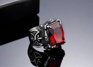 Macro detail of vintage titanium steel ring with large red gemstone and gothic cross patterns