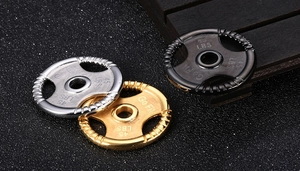 Macro detail of dumbbell weight plate pendants in silver, gold and black with Go Fit engraving