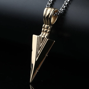 Close-up of golden arrowhead pendant with geometric V-lines on a stainless box chain