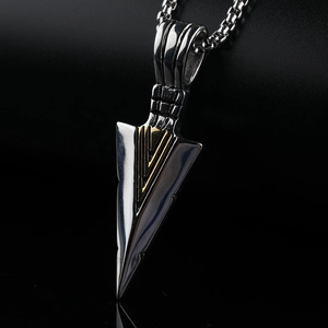 Macro shot of stainless steel arrow pendant with gold V-groove detail on a black box chain