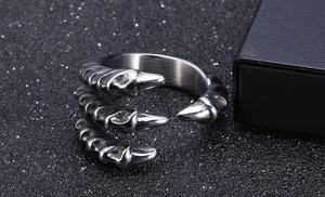 Macro shot of silver dragon claw ring with triple sharp talons on dark background