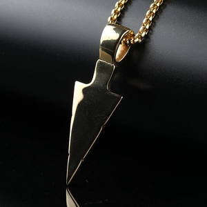 Macro shot of polished gold stainless steel arrowhead pendant on a sturdy box chain