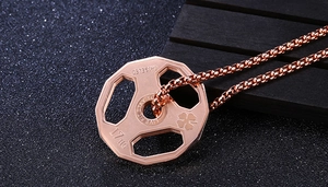Macro view of rose gold dumbbell pendant with detailed engraving on box chain necklace