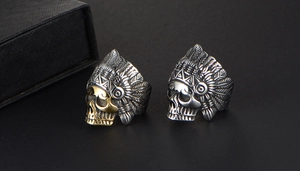 Macro shot of two vintage Indian chief skull rings in antique silver and gold finishes