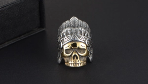 Detailed close-up of a punk Indian chief skull ring in silver and gold steel finish