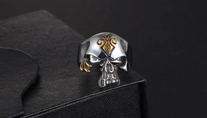 Detailopname van retro schedelring met gouden schop- en vleugelelementen op zwarte doos