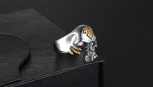 Detail van schedelring met gouden skelethanden en schoppensymbool op roestvrij staal
