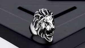 Close-up of a carved lion head ring in vintage silver finish with detailed mane texture