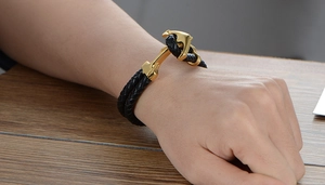 Dettaglio del bracciale maschile in pelle intrecciata con chiusura ancora dorata