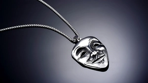 Macro detail of silver stainless steel Guy Fawkes mask pendant with polished mirror finish