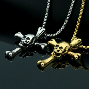 Détail de pendentifs tête de mort argentés et dorés avec chaîne box en acier inoxydable