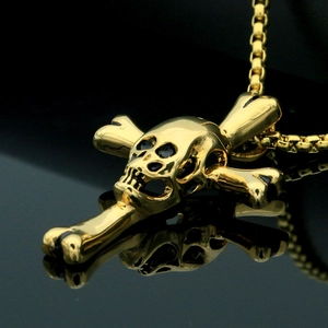 Vue macro latérale d'un pendentif tête de mort doré sur une surface noire réfléchissante