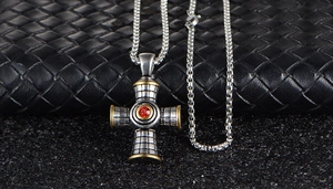 Close-up of gothic cross pendant with red gemstone and intricate silver grid textures