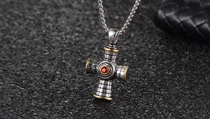 Detail view of a vintage stainless steel cross pendant with red gem and box chain