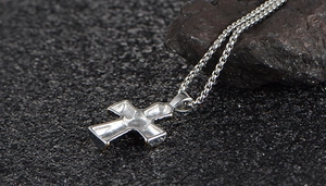 Detail view of a silver-toned cross pendant with textured grooves on a classic box chain