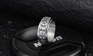 Macro shot of silver titanium steel spinning ring with embossed Buddhist mantra text