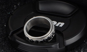 Macro shot of silver spinner ring with embossed industrial details and vintage steel finish