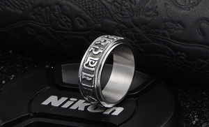 Macro detail of rotating stainless steel ring with engraved Buddhist mantra patterns