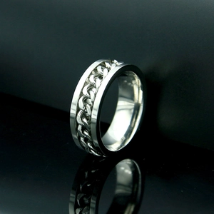 Primer plano de anillo giratorio de plata con diseño de cadena sobre fondo de espejo