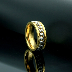 Detalle de un anillo de cadena giratorio bicolor oro y plata con diseño de estilo industrial