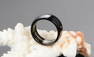Detail view of black polished ring featuring golden cross relief patterns on inner band