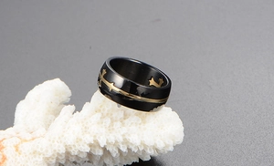 Macro shot of black titanium band with gold cross star pattern on a white coral support