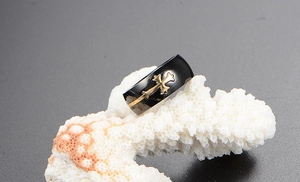 Macro view of a black titanium steel men's ring with a gold cross on a textured background