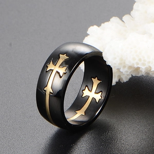 Men's black stainless steel wide ring with golden cross design on dark background