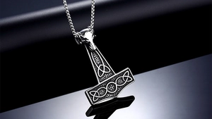 Close-up of stainless steel Mjolnir pendant with wolf head and Celtic knot carvings