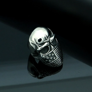 Detailed view of silver skull ring with American flag mask design on black reflective surface