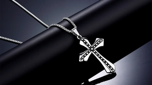 Detailed view of silver stainless steel cross pendant with black dotted textures