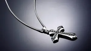 Macro shot of silver stainless steel cross pendant with black dotted texture and chain