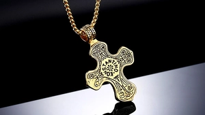 Detailed view of golden cross pendant with zircon inlay and ornate floral engravings