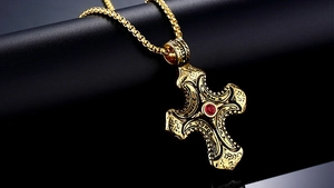Detailed macro view of vintage gold cross pendant with red zircon and hope honor engraving