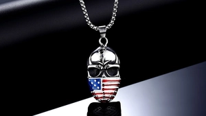 Detaillierte Makroansicht des silbernen Totenkopf-Anhängers mit US-Flagge auf schwarzem Grund