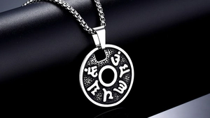 Macro detail of vintage titanium steel round pendant with relief mantra inscriptions