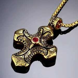 Vintage gold cross pendant necklace with a red gemstone and intricate relief texture