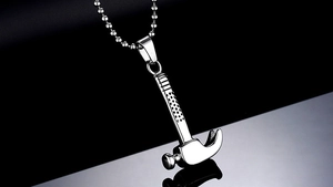 Macro shot of silver hammer pendant on ball chain with reflection on black surface