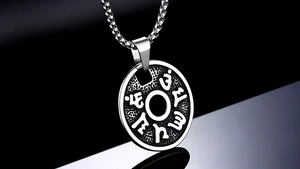 Detail of a vintage titanium steel mantra pendant with intricate relief and box chain