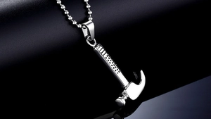 Close-up of a silver stainless steel hammer pendant on a bead chain with black background