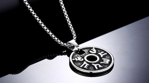 Macro shot of the Six-Character Mantra engraved on a titanium steel disc pendant