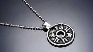 Detail of vintage silver mantra pendant featuring embossed relief on black texture