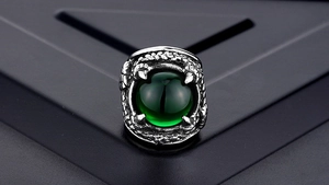 Macro shot of punk dragon claw ring detail with vibrant green gemstone in vintage steel