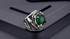 Macro shot of silver-tone dragon claw ring featuring a deep green cat's eye gemstone
