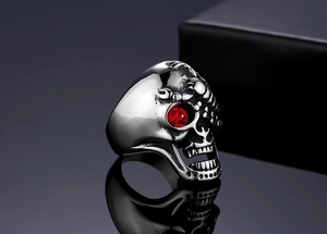 Gros plan sur bague crâne punk en acier avec œil rouge serti et reliefs de scorpion